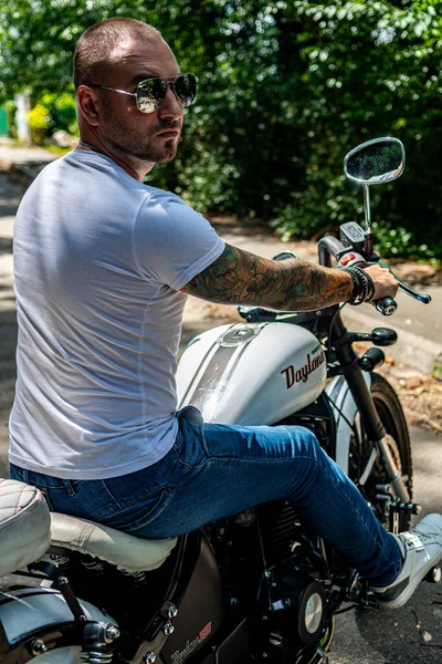 Kyiv 'deki Geon Daytona motosikletinde dövmeli, sakallı ve bilezikli genç yakışıklı bir adam.