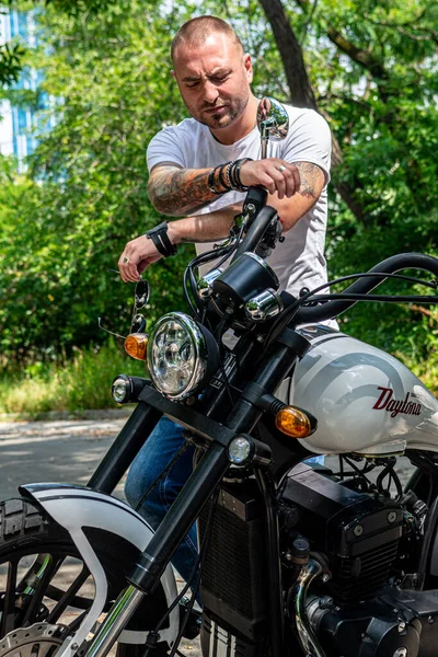 Kyiv 'deki Geon Daytona motosikletinde dövmeli, sakallı ve bilezikli genç yakışıklı bir adam.