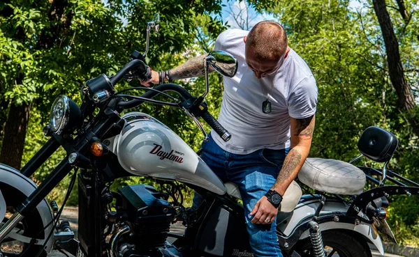 Kyiv 'deki Geon Daytona motosikletinde dövmeli, sakallı ve bilezikli genç yakışıklı bir adam.