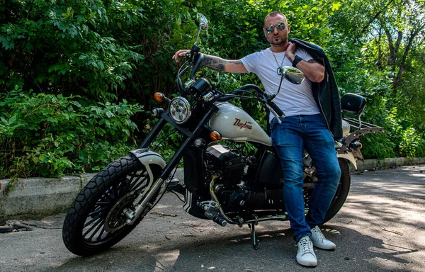 Kyiv 'deki Geon Daytona motosikletinde dövmeli, sakallı ve bilezikli genç yakışıklı bir adam.