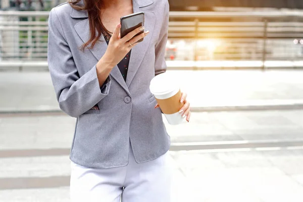 Business woman holding the mobile phone and coffee cup