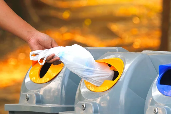 Hand throwing empty plastic bag into the recycling bin