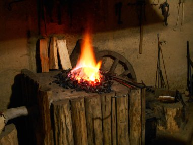 Demircinin araçlar arka plan üzerinde ahşap smithy yangında bir parlak kırmızı Alevi