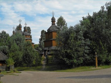 Eski ahşap kilise, hasır çit, yeşil çim ve ağaçların, mavi gökyüzü beyaz bulutlar ile