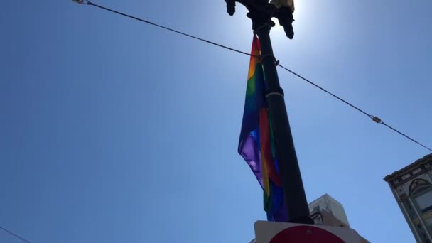 Низкий угол размахивания флагом геев на красивом голубом небе — стоковое видео