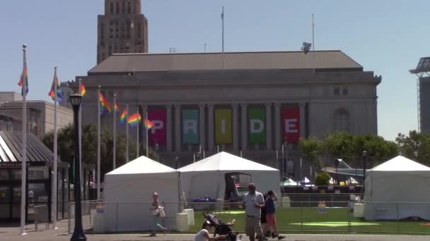 Ordet stolthet på en offentlig byggnad bredvid viftande homofile flaggor i San Francisco — Stockvideo