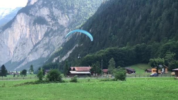スイスの谷の観光の町で女性とパラグライダー土地 — ストック動画