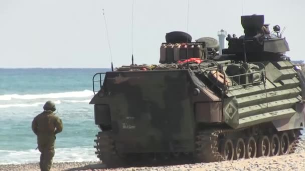 Vehículo anfibio atraviesa la costa y un soldado camina detrás de ella — Vídeo de stock
