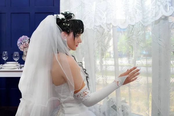 Bride in front of the window in anticipation of a loved one before the wedding.