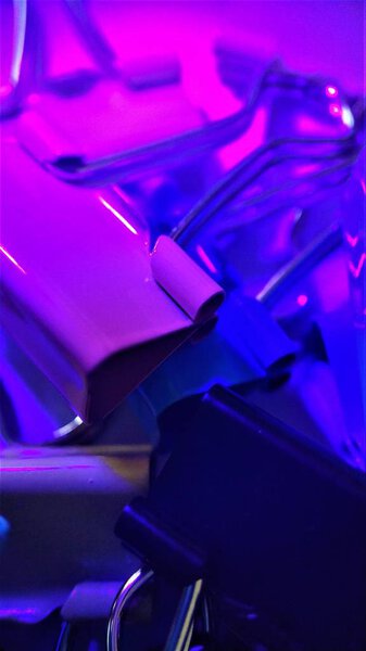 Colored paper clips under rays of ultraviolet macro closeup for background