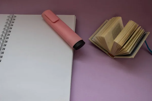 Notepad and pink marker on purple background