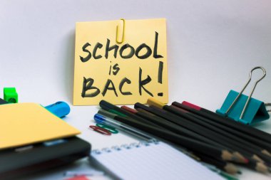 Okul kırtasiyesi, not defteri, kalemler, hafif bir arkaplan üzerine yazı