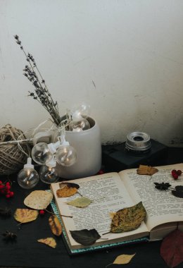 Koyu bir arkaplanda sonbahar kompozisyonu, rahat atmosfer, çay, kitaplar, yeşillik