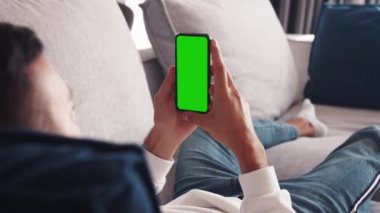 Kanepede uzanan adam krom anahtar yeşil ekranlı akıllı telefon kullanıyor, çeşitli hareketleri kaydırıyor - internet, iletişim konsepti 4k şablonu kapat
