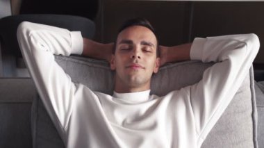 Kafkasyalı genç adam ellerini başının arkasına koyup koltukta dinleniyor.