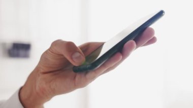 Bir evde ya da ofiste akıllı telefon kullanan genç bir adamın yavaş çekimde ellerini kapat.
