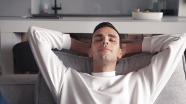 Kafkasyalı genç adam ellerini başının arkasına koyup koltukta dinleniyor.