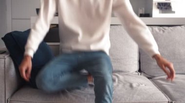 Yorgun, genç, beyaz bir adam yorucu bir çalışmadan sonra oturma odasında kanepede oturuyor. 4k ağır çekim görüntüleri.