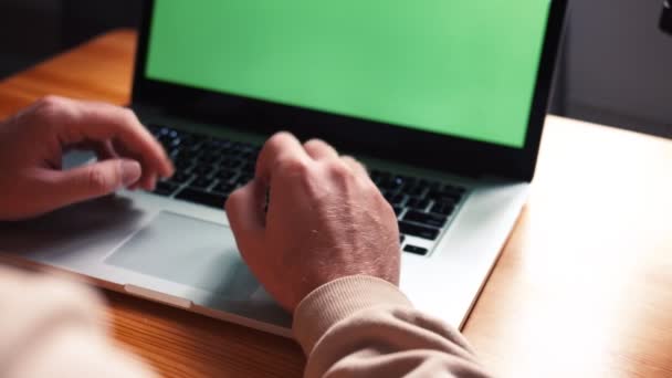Молодой кавказский человек в домашнем офисе сидит за столом и разговаривает с ноутбуком с зеленым экраном. Мужской разговор с помощью удаленной онлайн-конференции веб-камера видеозвонок — стоковое видео