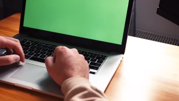 Молодой кавказский человек в домашнем офисе сидит за столом и разговаривает с ноутбуком с зеленым экраном. Мужской разговор с помощью удаленной онлайн-конференции веб-камера видеозвонок — стоковое видео