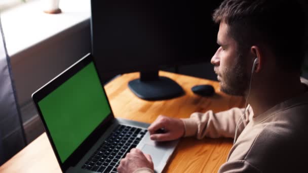 Jonge Kaukasische man op kantoor zit tafel communiceert praten praten met groene scherm laptop computer. man spreken door online remote conferentie web cam video oproep — Stockvideo