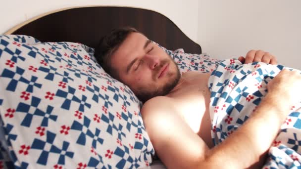 年轻的高加索人早上睡在床上。男人一个人躺在大床上. — 图库视频影像