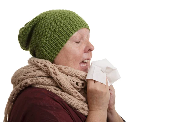 一位年长的妇女在冬天的时候有疾病要打喷嚏和吹成手帕孤立的白色背景 — 图库照片