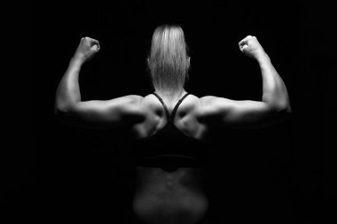 Kadın vücut geliştirmeci koyu arka plan üzerinde poz