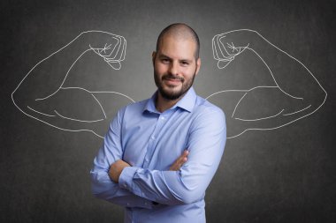 Bir gri yazı tahtası arka plan önünde kas silah duran iş adam. Takım oluşturma ve motive genç meslektaşları kavramı.