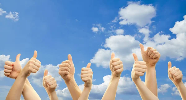 Hands and thumbs up in front of blue sky and white clouds. Concept for sucess and ecology.