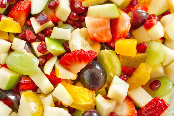 Fruit salad with oranges, grapes, pomegranate seeds, strawberries, apples