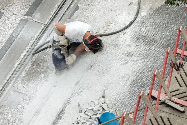 Kaldırımda çalışan matkap ile yol işçisi.