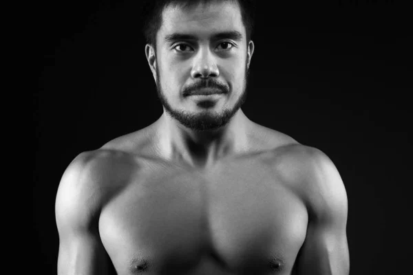 Strong young man with perfect figure on dark background