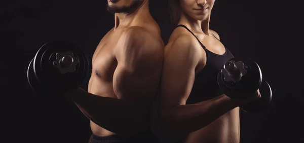 Koyu arka plan üzerinde dumbbells ile sportif Çift