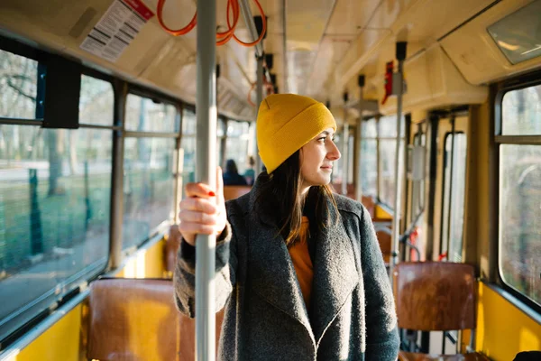 Young woman standing in a wagon of a driving tramway. Transportation, travel and lifestyle concept.