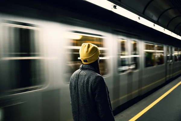 Tren gelene kadar genç bir kadın metro istasyonunda bekliyor. Ulaşım ve seyahat kavramı.