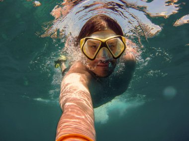 Şnorkel ve dalış maskesi ile genç adam yüzme ve bir sel alarak