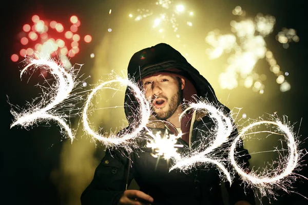 Man celebrating New Year's Eve with fireworks and writing the nu — Stock Photo, Image
