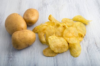 Beyaz ahşap zemin üzerinde ham patates cipsi