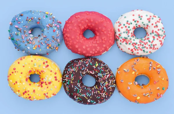 Set van donuts van verschillende kleuren, blauwe achtergrond. — Stockfoto