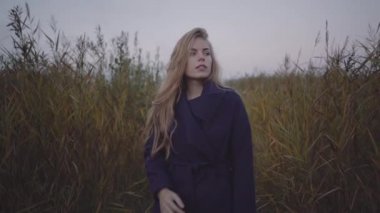 Bir kadın değil bir ceket bir iskele boyunca uzun otların arasında yürüyor.