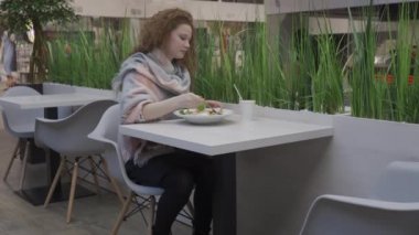 genç güzel kadın bir kafede Sezar salatası yiyor