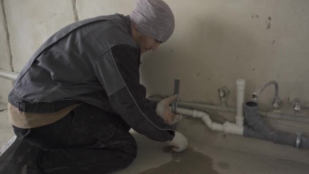 Bauarbeiter in Arbeitskleidung befestigt Rohre an der Wand — Stockvideo