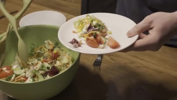 Мужчина кладет салат в тарелку — стоковое видео