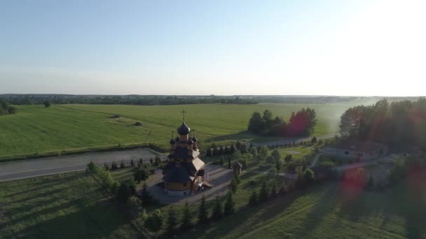 Vista aérea em torno da igreja contra o pano de fundo de um campo e floresta — Vídeo de Stock