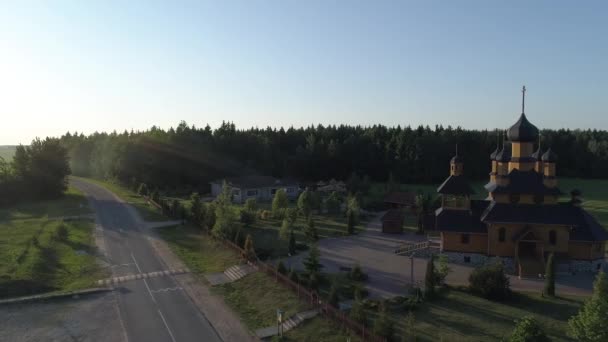 Antenn flyingover kyrkan mot bakgrund av åkrar och skogar — Stockvideo
