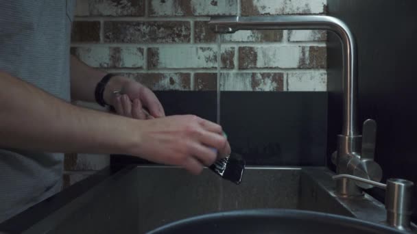 Un hombre lava una espátula con una esponja para lavar en la cocina — Vídeo de stock