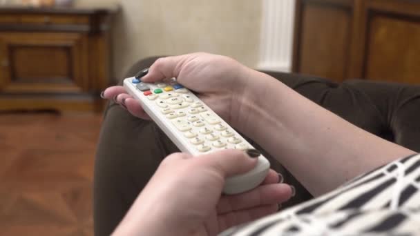 Mujer presiona los botones en el control remoto — Vídeo de stock