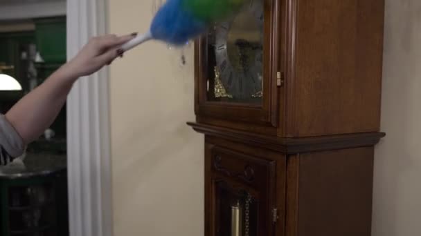 Vrouw reinigt de grote klok uit stof met een borstel. Huis reiniging concept — Stockvideo