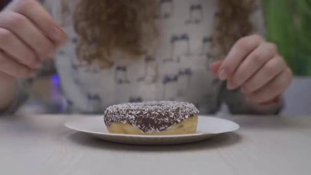 Ung vacker kvinna med rött hår plockar upp en chocolate donut — Stockvideo